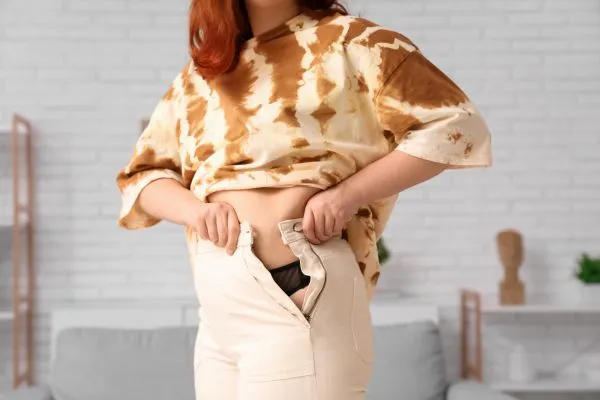 Image of woman trying to do her trousers up after pregnancy weight gain Beeston Hill