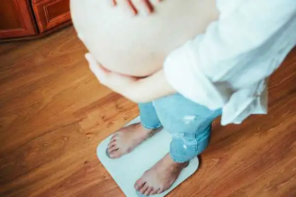 Image of woman weighing herself and experiencing weight gain through pregnancy Beeston Hill